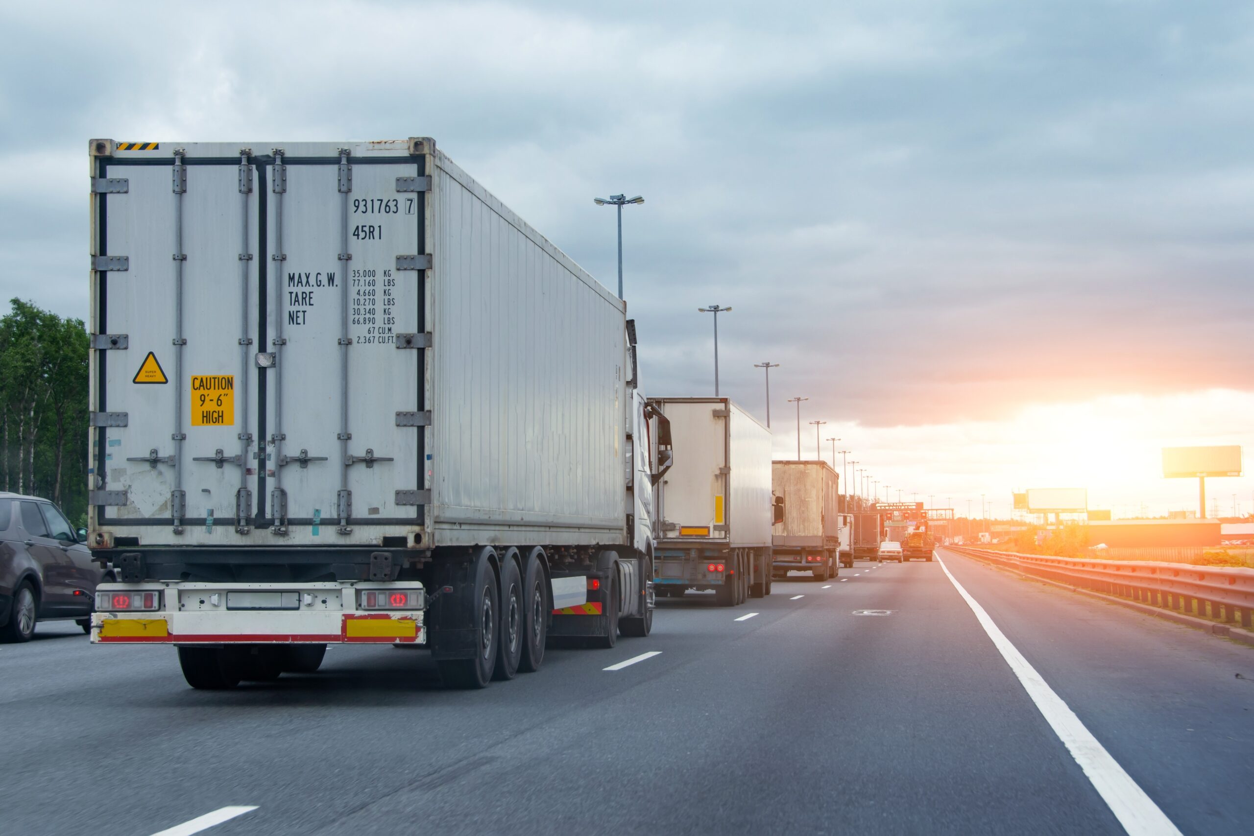 Trucks traveling on a highway at sunset.