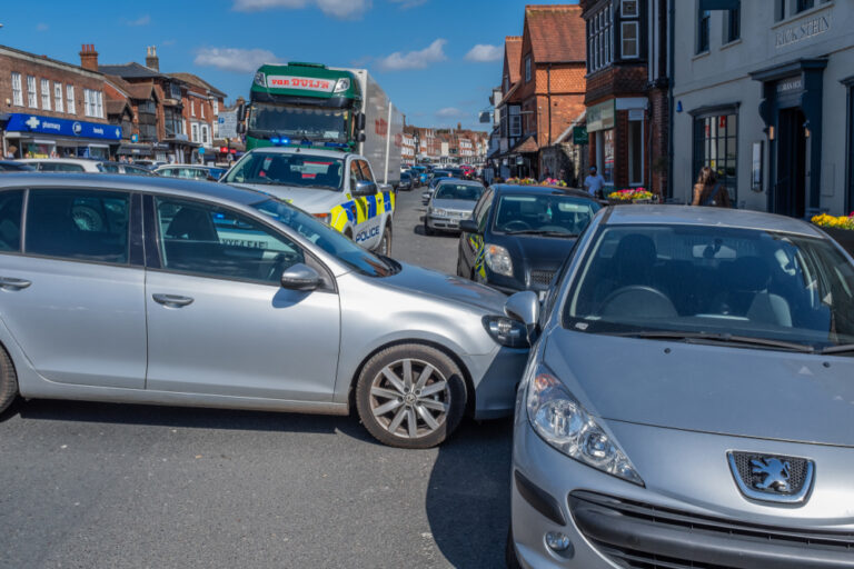 Two cars on a street, with a police vehicle nearby.