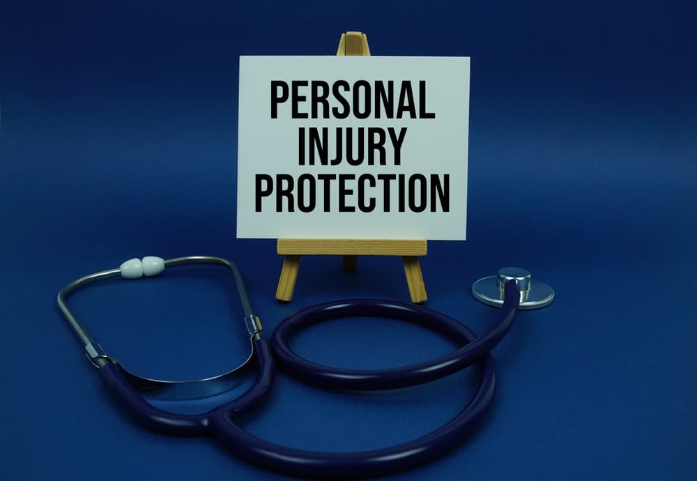 Personal Injury Protection text message on paper card with stethoscope on wooden background