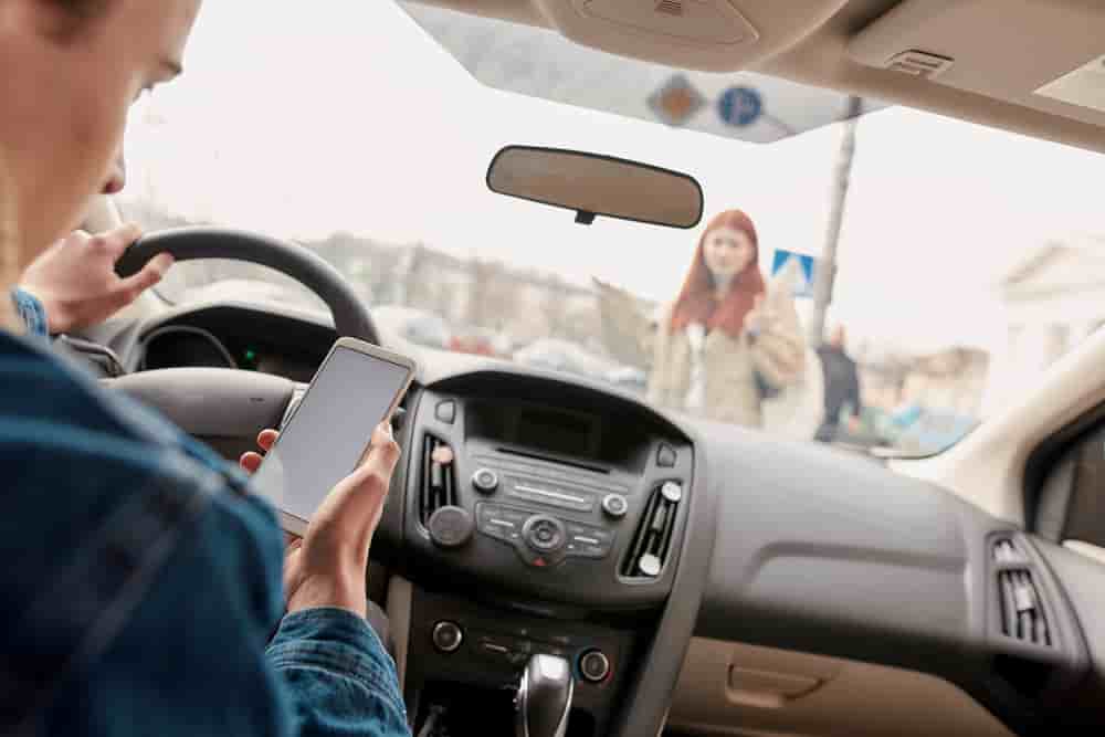 Distracted young male driver looking at the screen of his mobile phone while running over a pedestrian