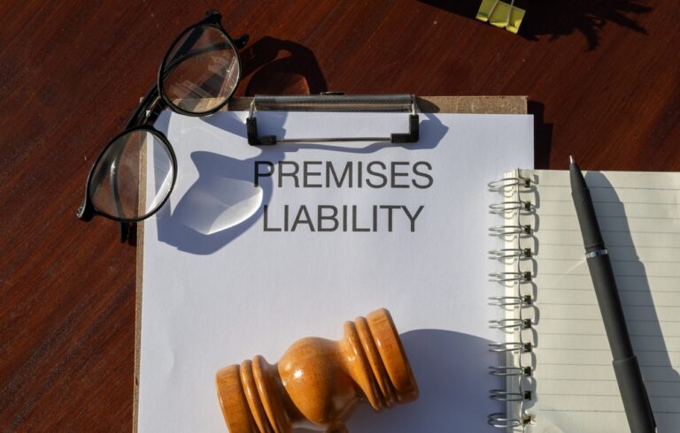 A gavel, eyeglasses, and notebook beside a clipboard labeled Premises Liability.