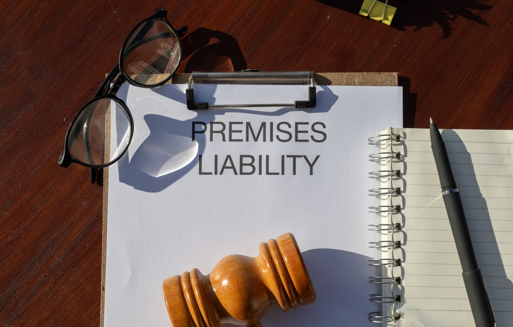 A gavel, eyeglasses, and notebook beside a clipboard labeled Premises Liability.