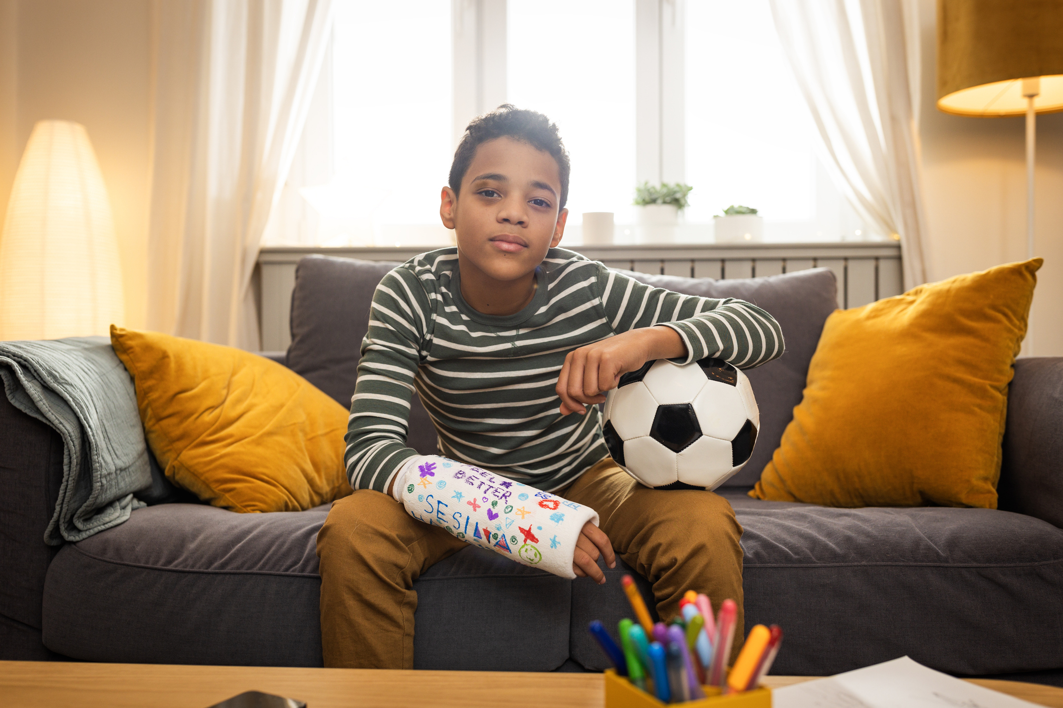 Child Injury Lawyer - Young boy with a broken arm resting at home with his dog