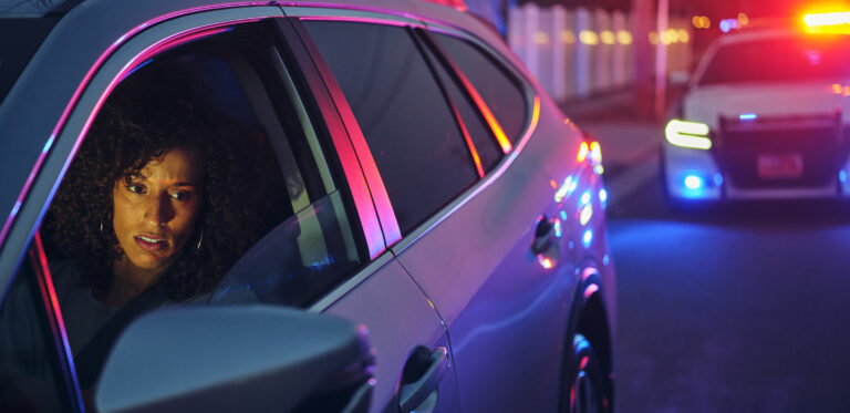 A police officer speaking with a woman during a nighttime traffic stop.