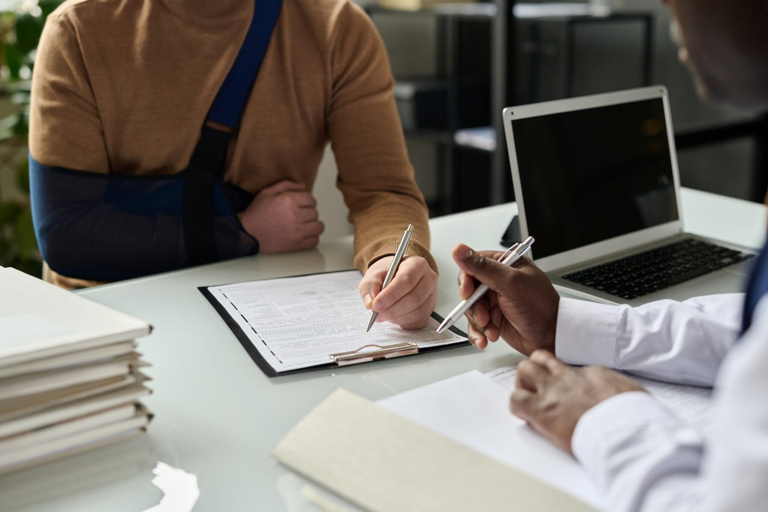 Person with an arm sling completing care paperwork after an injury