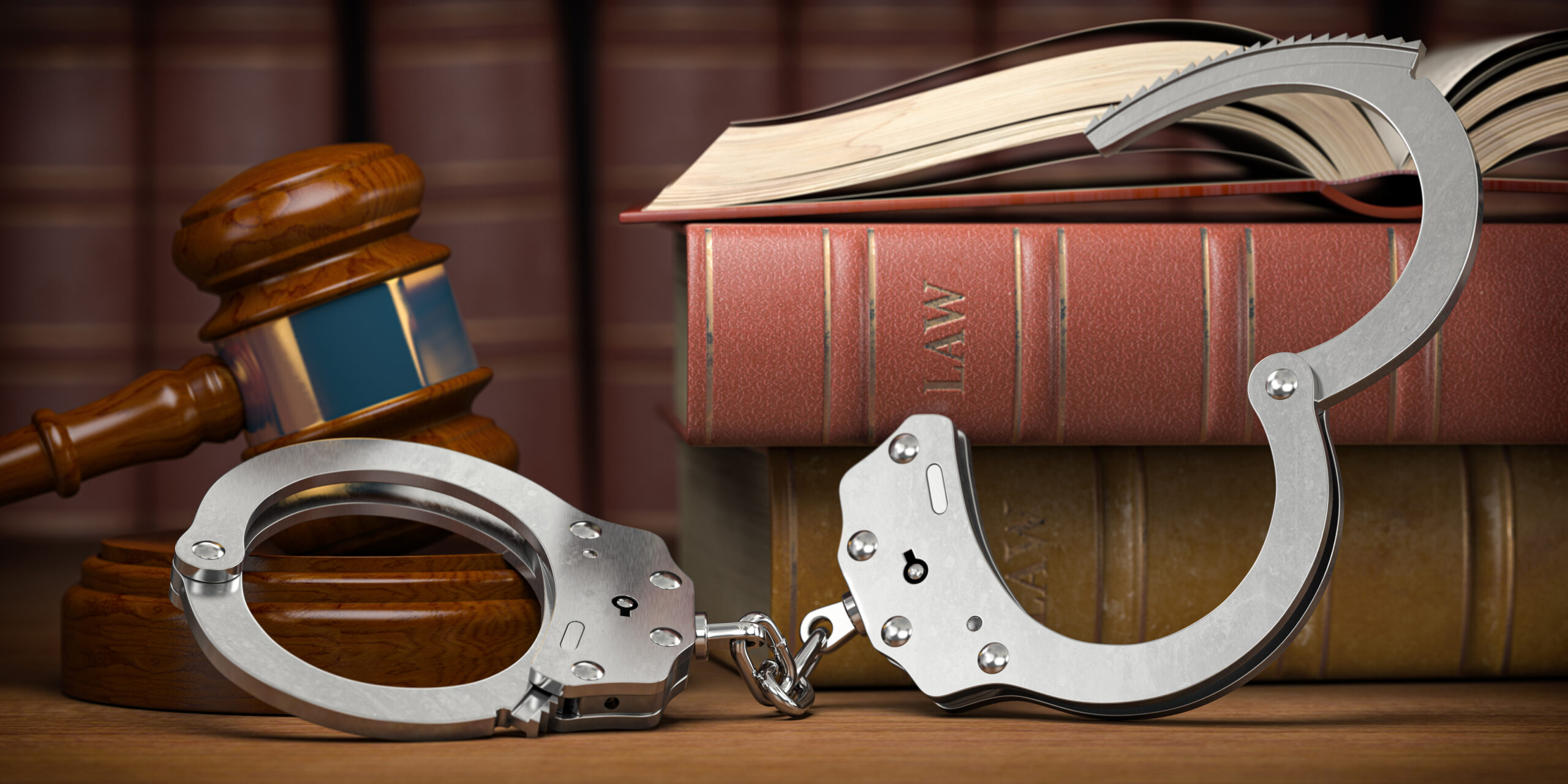 Handcuffs, a gavel, and law books on a table