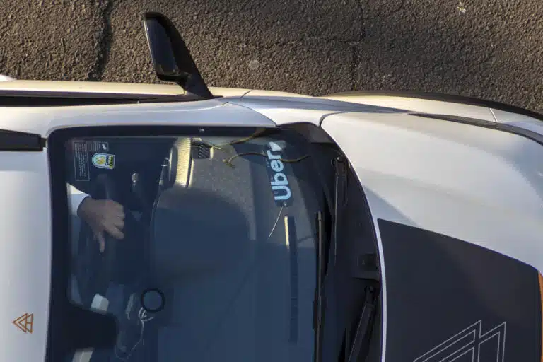 Overhead view of a white car with an Uber sign on the windshield