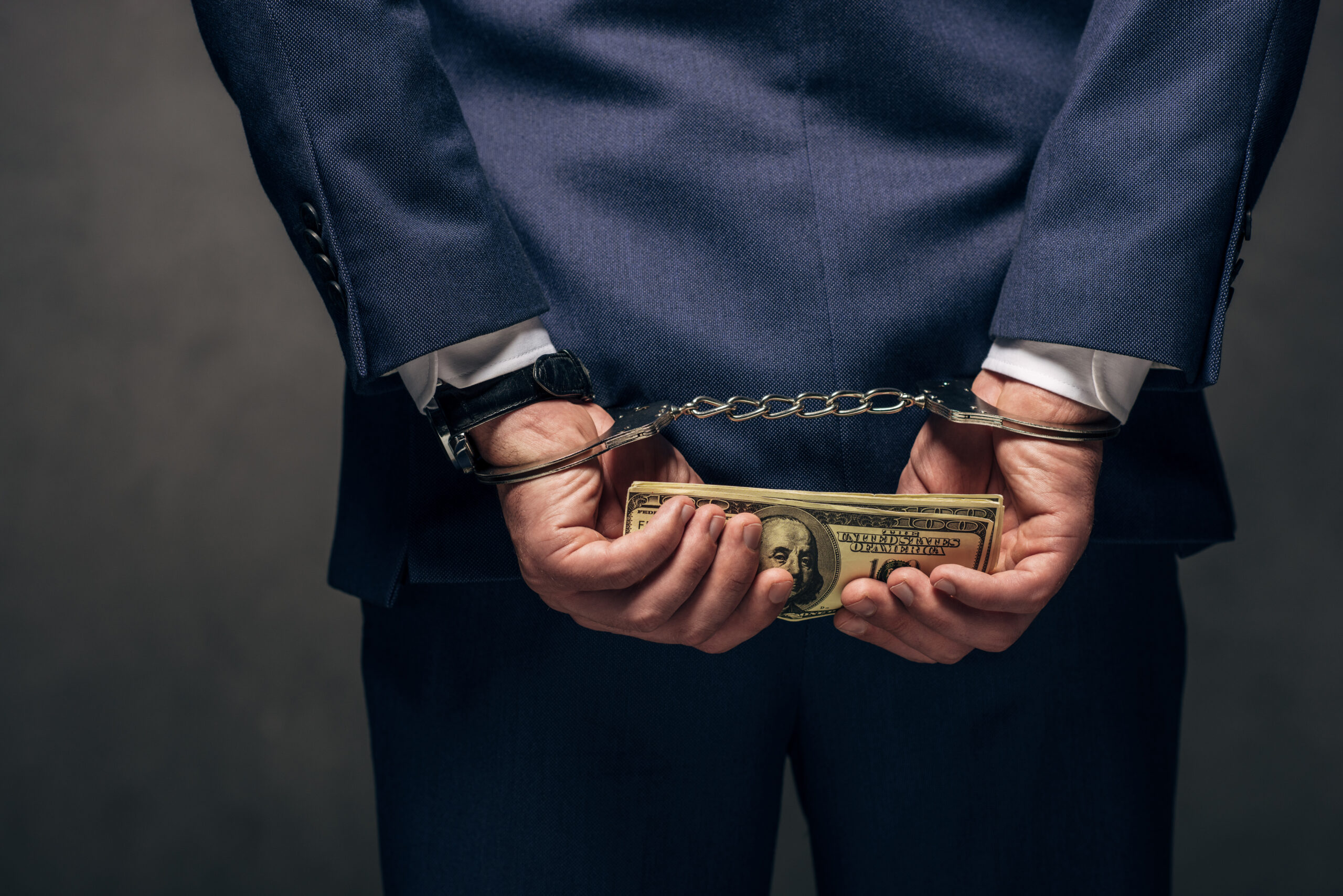 Man holding cash in handcuffs, illustrating fraud defense in Pompano Beach